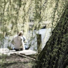 Ein Pärchen, das am Fluss hinter einem Baum sitzt