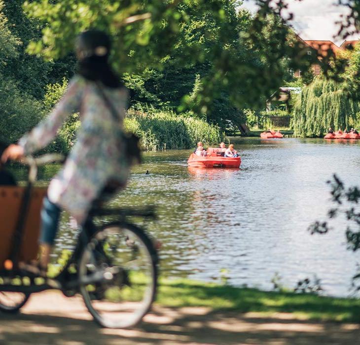 Kvinde på christianiacykel med vandcykler på aaen i baggrunden